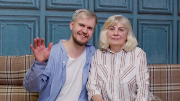 Familia de mayor madre de pelo gris y apuesto hijo adulto o nieto saludando, hola, bienvenido — Vídeos de Stock