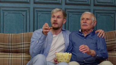 Mutlu farklı erkek nesiller TV seyrederek duygusal futbol şampiyonluğunu kutluyorlar.