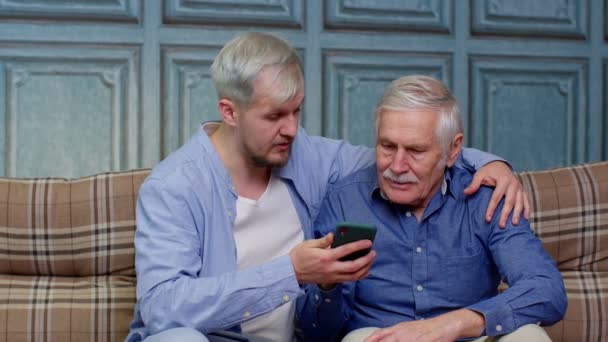 Happy famille père aîné et fils regardant sur téléphone mobile à Internet en ligne avec plaisir ensemble — Video