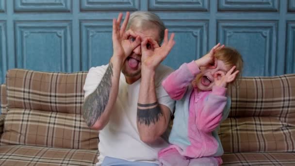 Far og barn datter barn i pyjamas narre sidde på sofaen i stuen smil se på kameraet – Stock-video