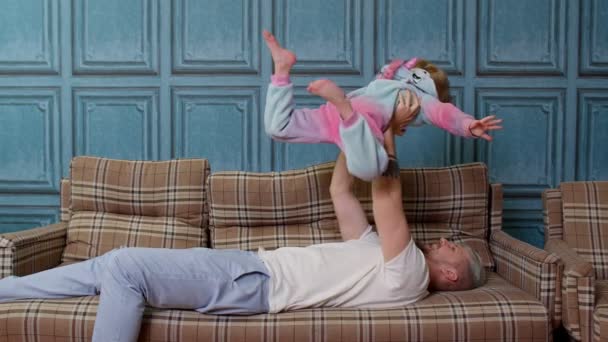 Bambino ragazza che vola come aereo, gioco a ridere con il giovane padre, rilassarsi sul divano a casa — Video Stock