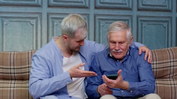 Diferentes gerações masculinas família descansando, usando aplicativos móveis, compras na loja online — Vídeo de Stock
