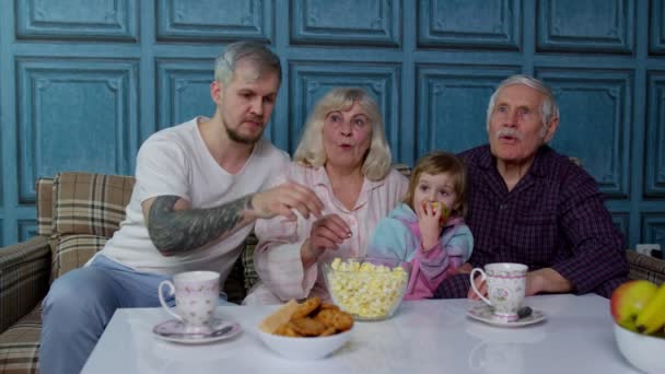 Familia multigeneracional asustándose, viendo películas de televisión de terror, comiendo palomitas en casa — Vídeo de stock