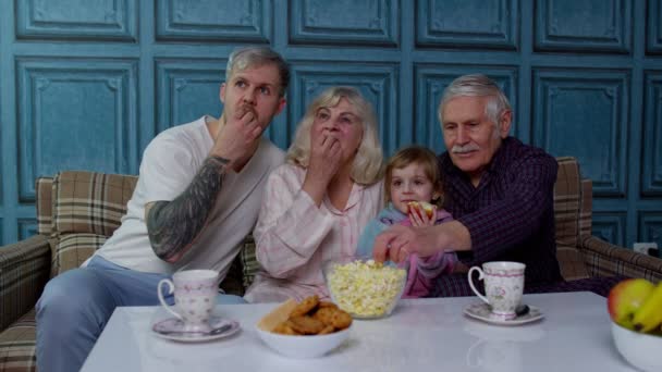 Familia multigeneracional ver la televisión con el niño joven en casa, asustarse viendo película de terror — Vídeo de stock