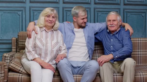 Семья старших бабушки и дедушки со взрослым сыном, которые развлекаются, глядя на домашнюю камеру — стоковое видео