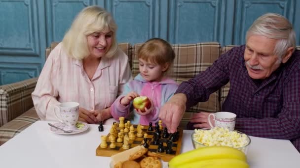 Ώριμη γιαγιά παππούς με παιδί το εγγόνι κορίτσι παίζει σκάκι παιχνίδι με στο τραπέζι στο δωμάτιο — Αρχείο Βίντεο