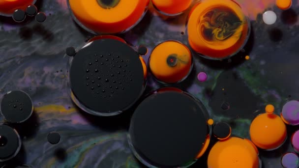 Рух зверху чорного помаранчевого масляного чорнила краплі бульбашки, різнокольоровий художній фон фарби — стокове відео