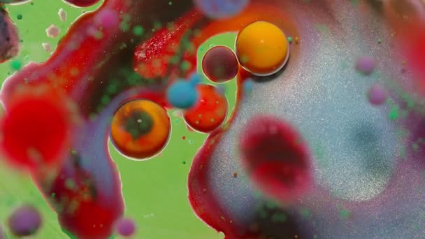 Бульбашки плавають у рідкій фарбі, змішуючи чорнило, олію та молоко, абстрактний багатобарвний гіпнотичний живопис — стокове відео