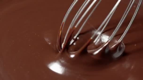 Slow motion mengen, roeren premium donkere gesmolten chocolade met een garde, proces van het maken van snoep — Stockvideo