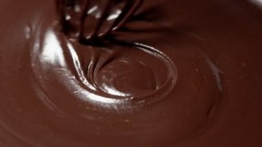 Şefin karıştırdığı eritilmiş sıvı siyah çikolata ve çırpılmış el yapımı şekerler.