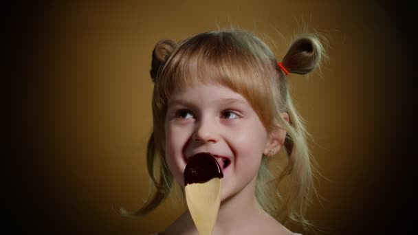 Glückliches kleines Mädchen leckt geschmolzene Schokolade, Kind isst, genießt ungesundes süßes Essen im Haus — Stockvideo