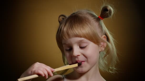 在演播室里，一个笑容可亲的小女孩被融化的巧克力弄得面色苍白 — 图库视频影像