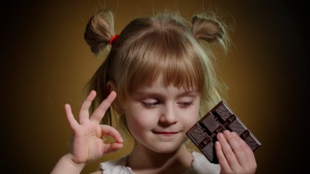 Retrato de adolescente sorridente criança criança menina com barra de chocolate de leite mostrando polegar até gesto, ok sinal — Vídeo de Stock