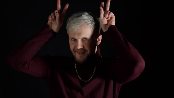 Lustige fröhliche Mann in stilvoller Bluse macht Hasenohren Hand Geste über den Kopf auf schwarzem Hintergrund — Stockvideo