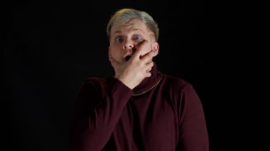 Şaşırmış stil sahibi bir adam heyecan hissediyor, kameraya bakıyor ve yüzüne yakın el ele tutuşuyor.