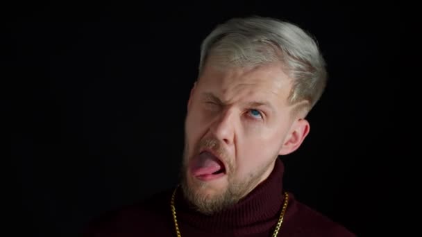Комический глупый стильный мужчина делает смешные глупые гримасы лица, изображая дурака, показывая язык, безмозглый — стоковое видео