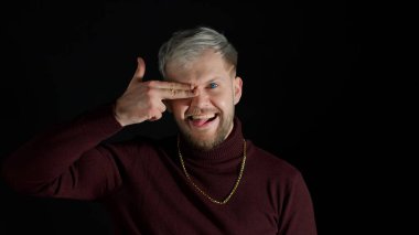 Şık bir adam parmak tabancasıyla işaret ediyor, kendinden emin görünüyor, tabancayla öldürüyor.