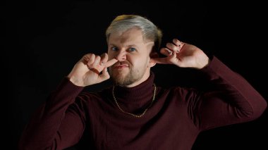 Komik, aptal bir stil adamı burun ve kulak karıştırıyor, sümük çıkarıyor, kültürsüz alışkanlıklar ediniyor, kötü davranışlar sergiliyor.