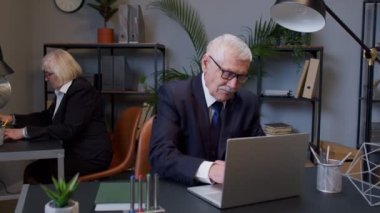 Modern ofis içinde çalışan yaşlı patron, yeni bir proje geliştiriyor.