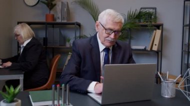 Üst düzey işletme yöneticisi masa başında çalışıyor, dans ediyor, zaferi kutluyor, iyi bir sonuç elde ediyor.