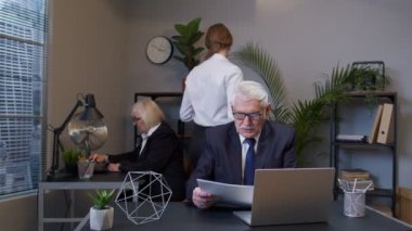 Memnun olmayan olgun muhasebeci mali belgeleri inceledikten sonra belgeleri fırlatıyor.