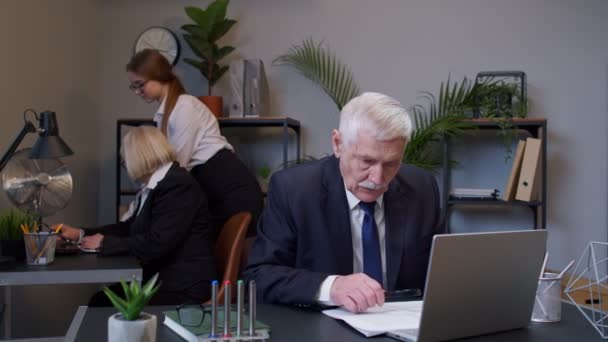 Un vieil homme comptable lisant des documents, analysant des documents financiers levant la main avec surprise — Video