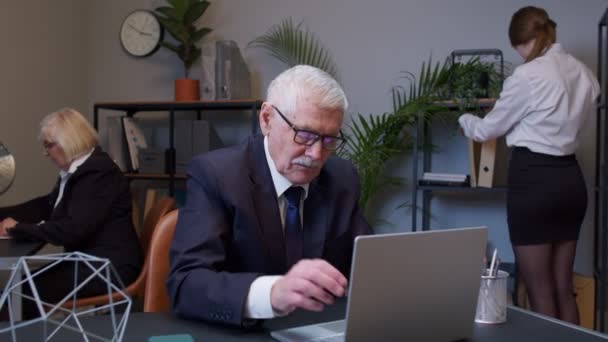 Znudzony starszy szef robi gest dłoni twarzy podczas tworzenia nowego projektu na laptopie — Wideo stockowe