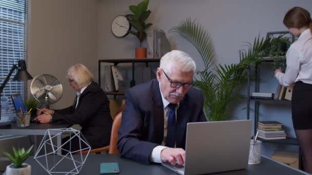 Senior verveelde, vermoeide mannelijke professionele manager webdesigner maakt online werk op kantoor — Stockvideo