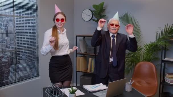 Усміхнений секретар з красивим старшим бізнесменом директором компанії танцює танець перемоги в офісі — стокове відео