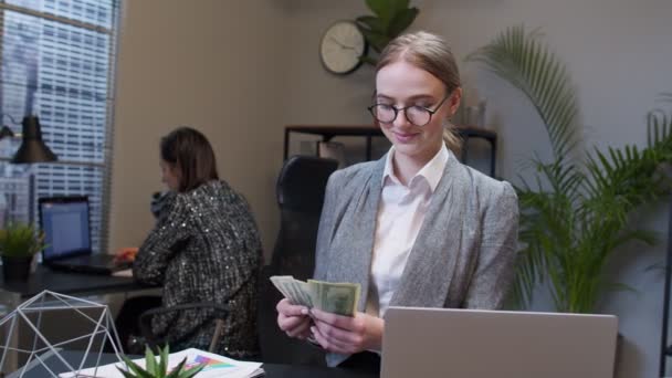 在办公室的笔记本电脑上工作后，快乐而富有的女经理在数钱 — 图库视频影像