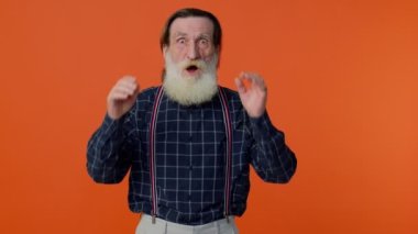 Heyecanlı yaşlı adam şaşkınlıkla el kaldırıyor kameraya bakıyor, ani bir zaferle şoke oluyor.