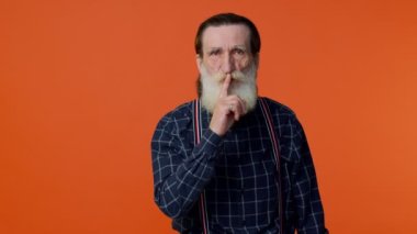 Yaşlı sakallı adam işaret parmağını dudaklarına bastırıyor sessiz hareket işareti yapıyor.