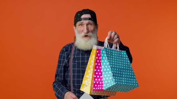 Anciano barbudo hombre mostrando bolsas de compras y hasta 70 por ciento de descuento inscripciones texto, Viernes Negro — Vídeo de stock