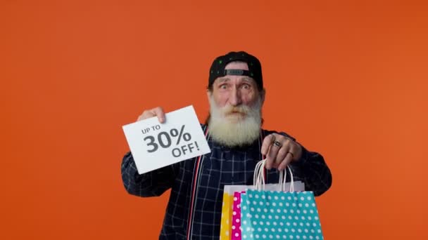 Anciano barbudo hombre mostrando bolsas de compras y hasta 30 por ciento de descuento inscripciones texto, Viernes Negro — Vídeos de Stock