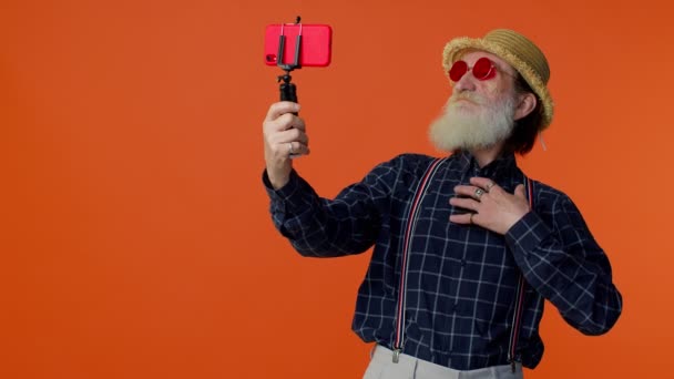 Зрілий дід мандрівник блогер в сонцезахисних окулярах, приймаючи селфі на мобільний телефон, відеодзвінок онлайн — стокове відео
