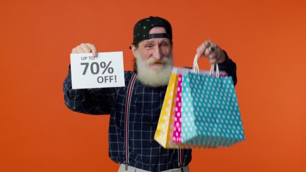 Homem barbudo sênior mostrando sacos de compras e até 70% Off banner inscrições, Black Friday — Vídeo de Stock