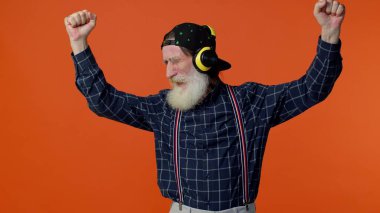 Yaşlı adam kulaklıkla müzik dinliyor, disko dansı yapıyor, el kol hareketleri yaparak eğleniyor.