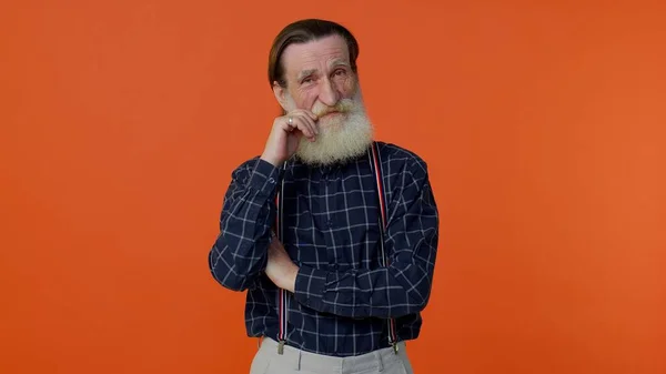 Vieil homme souriant âgé aux cheveux gris regardant la caméra, fixant la barbe posant sur fond orange — Photo