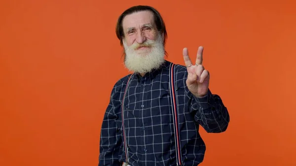 Senior bearded man showing victory sign, hoping for success and win, doing peace gesture and smiling — Stock Photo, Image