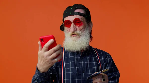 Старший старый стильный бородатый мужчина, используя кредитную карту и смартфон покупки онлайн покупки — стоковое фото
