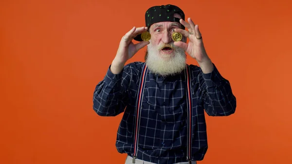 Пожилой старый бородатый стильный мужчина с золотыми биткойнами, инвестициями в криптовалюту, горной технологией — стоковое фото