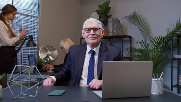 Босс-пожилой человек, работающий в современном интерьере офиса, старший фрилансер, смотрящий в камеру — стоковое фото