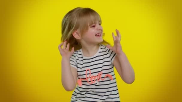 Смешная девочка в полосатой футболке слушает музыку, улыбается, танцует под музыку диско, веселится — стоковое видео