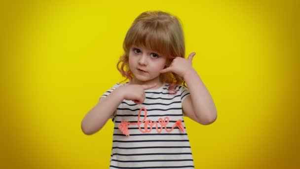 Klein schattig blond kind meisje kijken naar camera doen telefoon gebaar als zegt hey bel me terug — Stockvideo