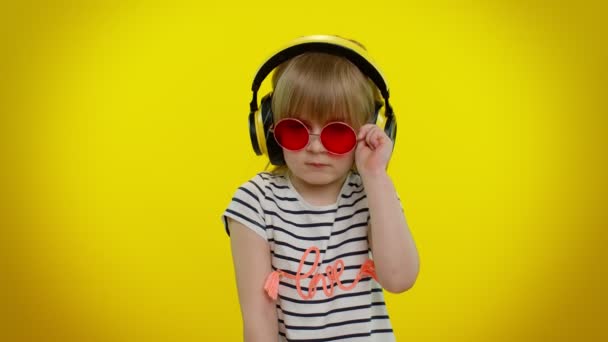 Усміхнена мила дівчинка в навушниках слухає музику блимає око, посміхається, підморгує, фліртує — стокове відео