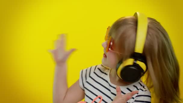 Zabawny zabawny mały dzieciak dziewczynka słuchanie muzyki przez słuchawki, taniec disco oszukiwanie zabawy — Wideo stockowe