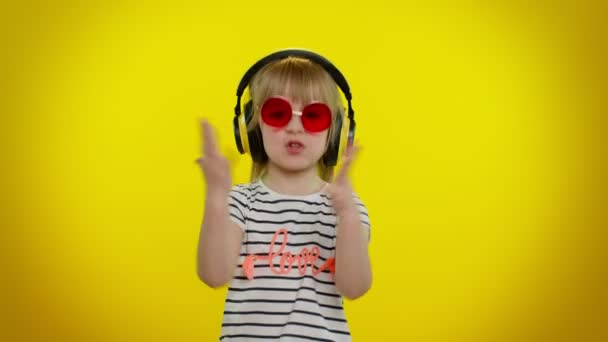 Young blonde teen kid child girl listening music via headphones, dancing disco fooling, having fun — Stock Video
