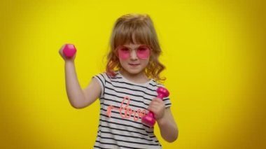 Sportif kız antrenman yapıyor, kol kaslarını şişiriyor pembe dambılları kaldırıyor, pilates yapıyor.