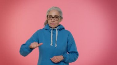 Üzgün, yaşlı bir kadın işaret dilini gösteriyor. İfade veriyor, onaylamıyor, tatmin olmuyor, hoşlanmıyor.