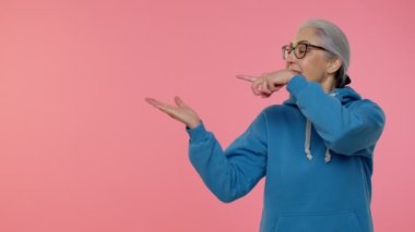 Yaşlı yaşlı kadın boş alanda baş parmağını gösteriyor ve solu işaret ediyor, reklam logosu.